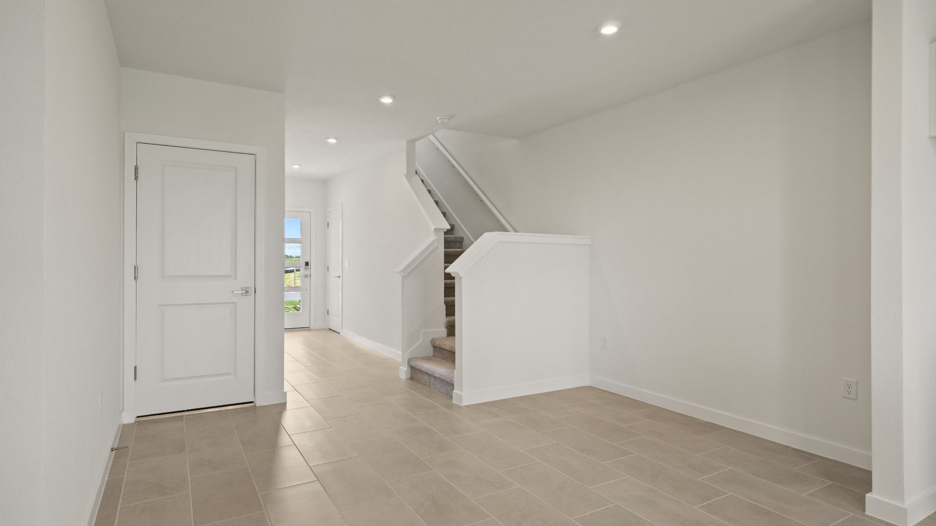 Spacious entryway features sleek flooring, recessed lighting, and a contemporary staircase design