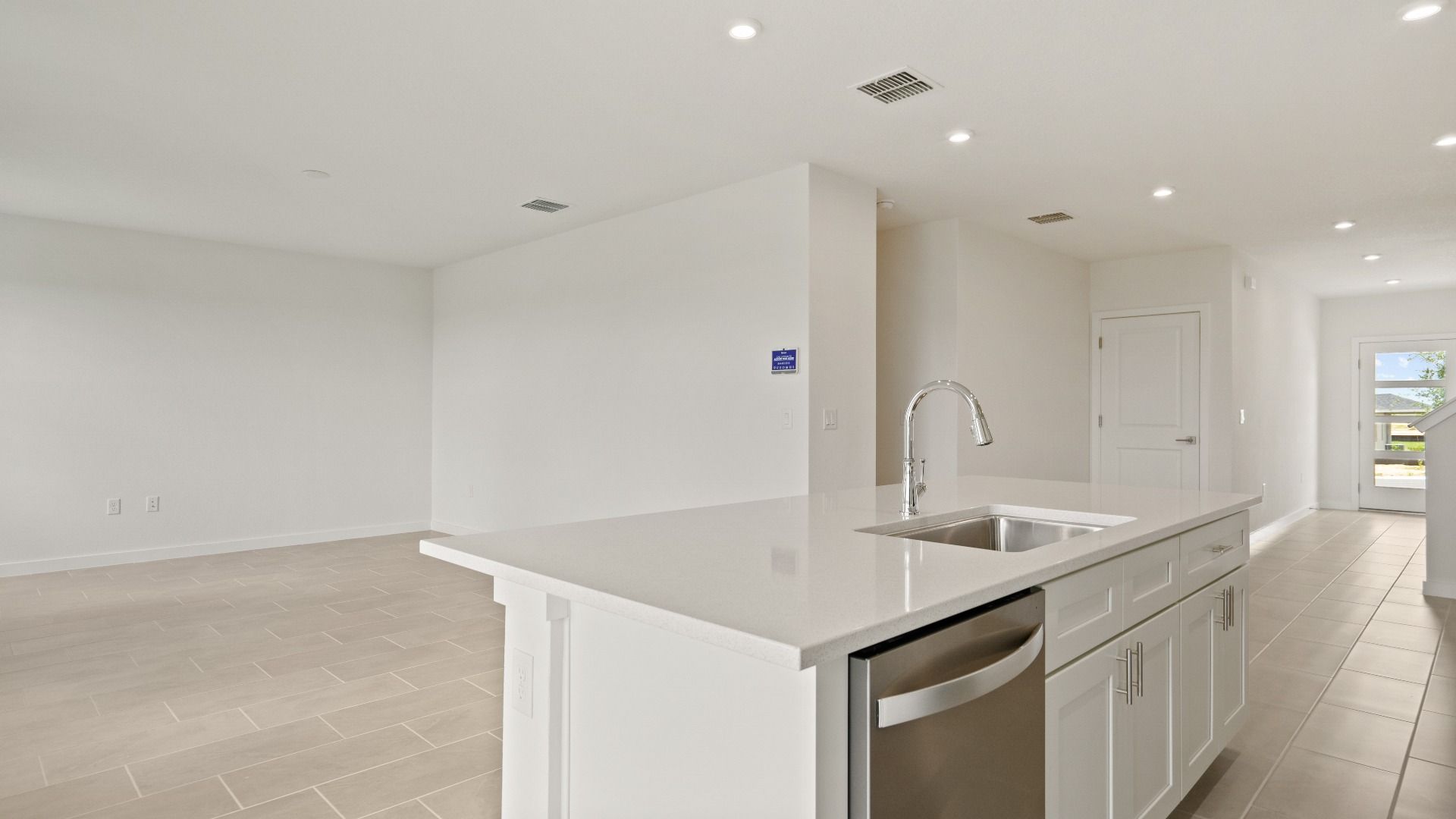 Spacious living area flows seamlessly from the kitchen, featuring tile floors, recessed lighting, and an open layout
