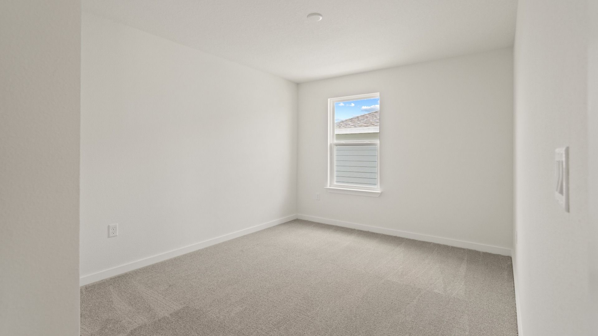Comfortable third bedroom with soft carpet and natural light—perfect for a guest room, nursery, or private workspace