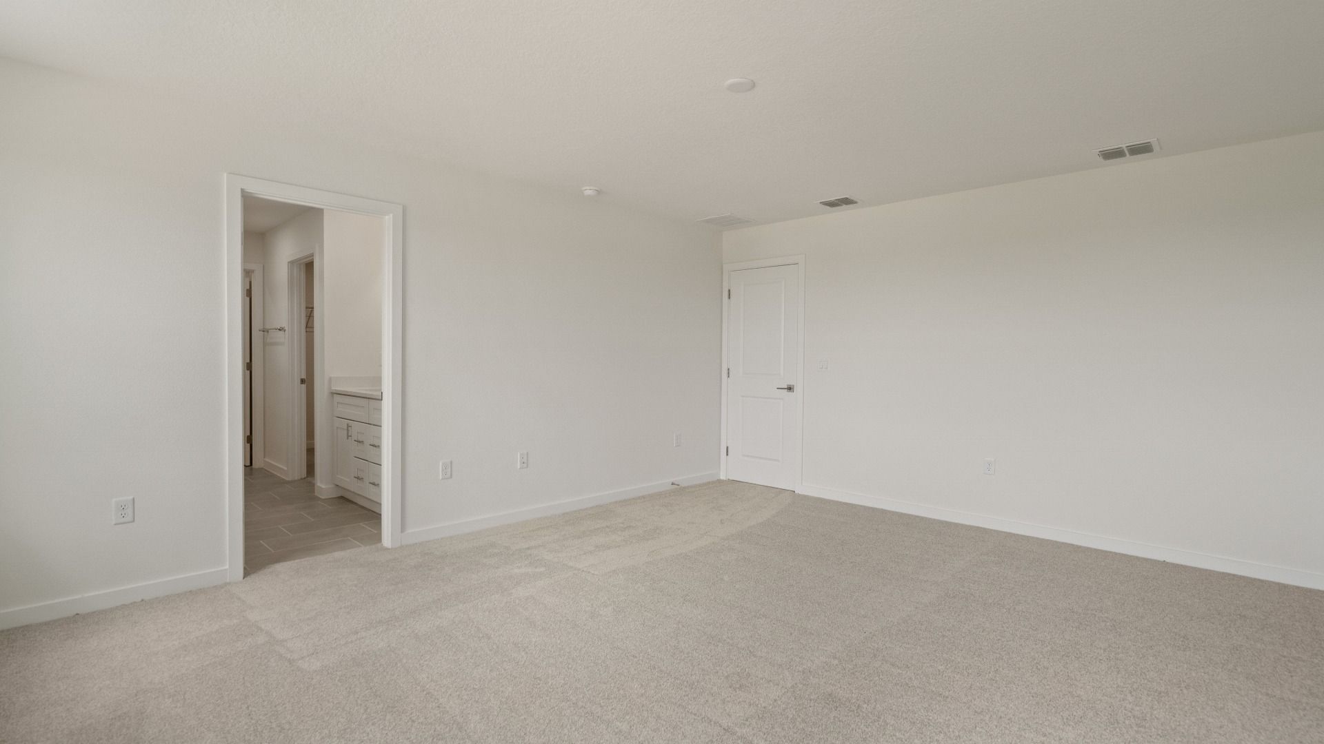 Expansive primary suite offers comfort and privacy with soft carpet, generous layout, and attached ensuite bath