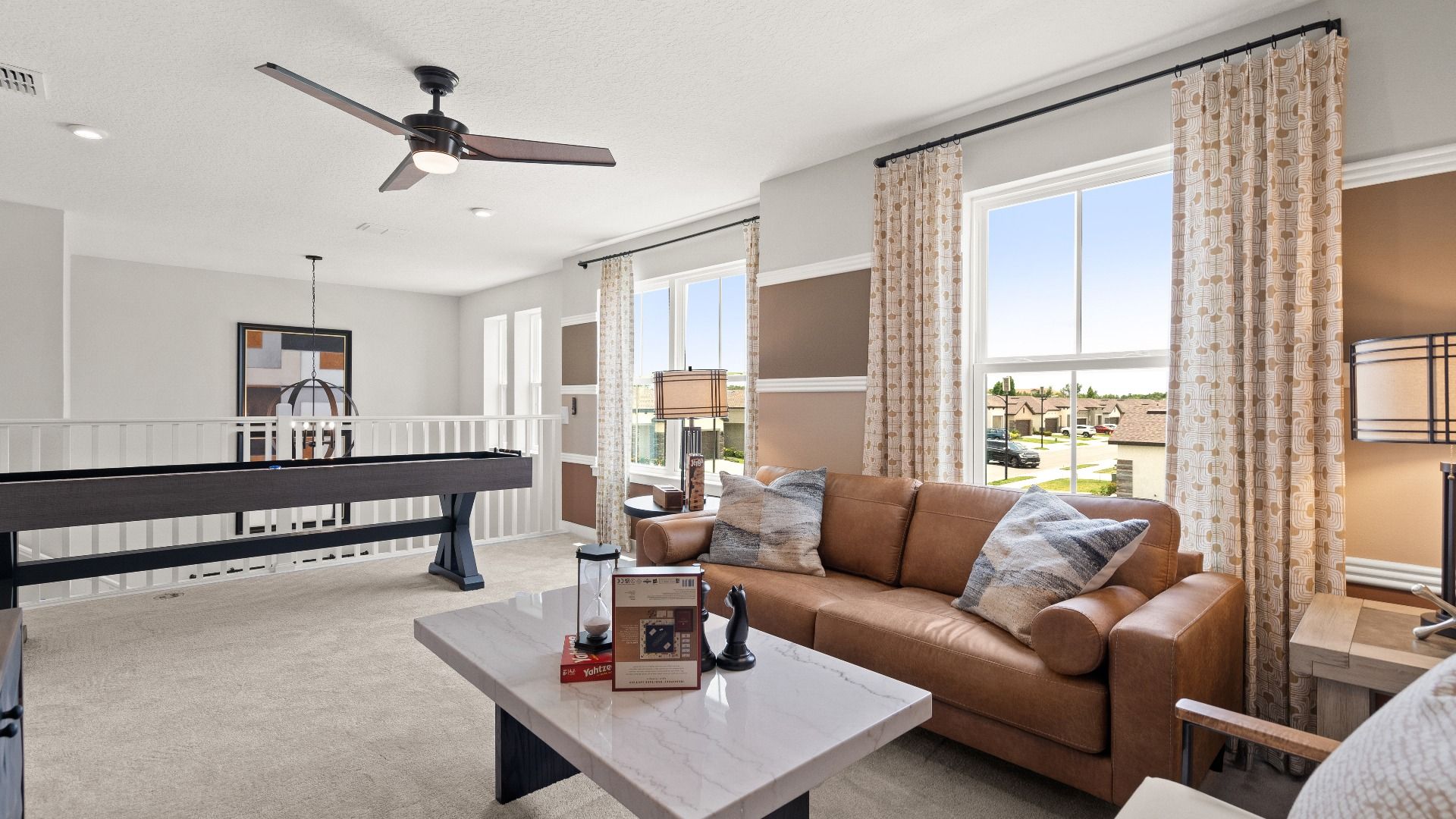 Upstairs flex area with shuffleboard, lounge area, and large windows in the Jupiter Model at Grasslands West in Lakeland, FL.