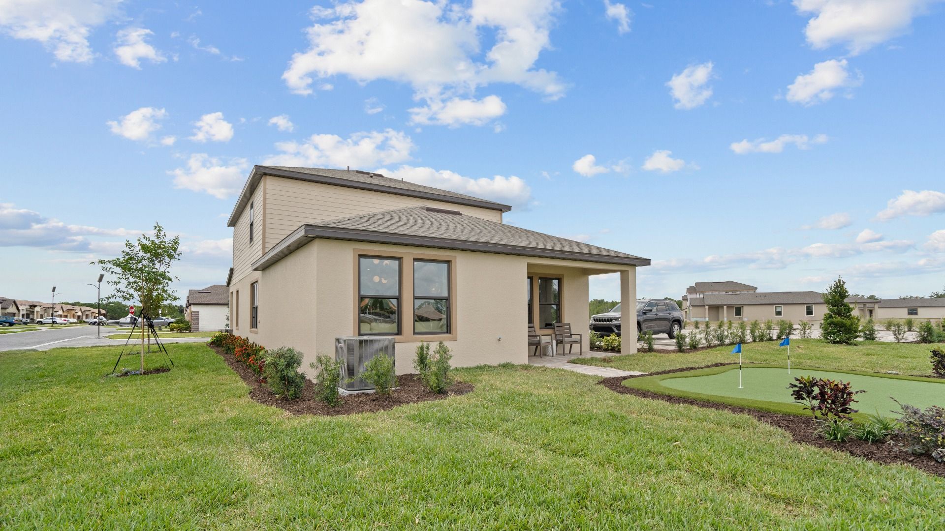 A golfers dream with a private putting green and covered patio backyard of the Jupiter Model at Grasslands West.