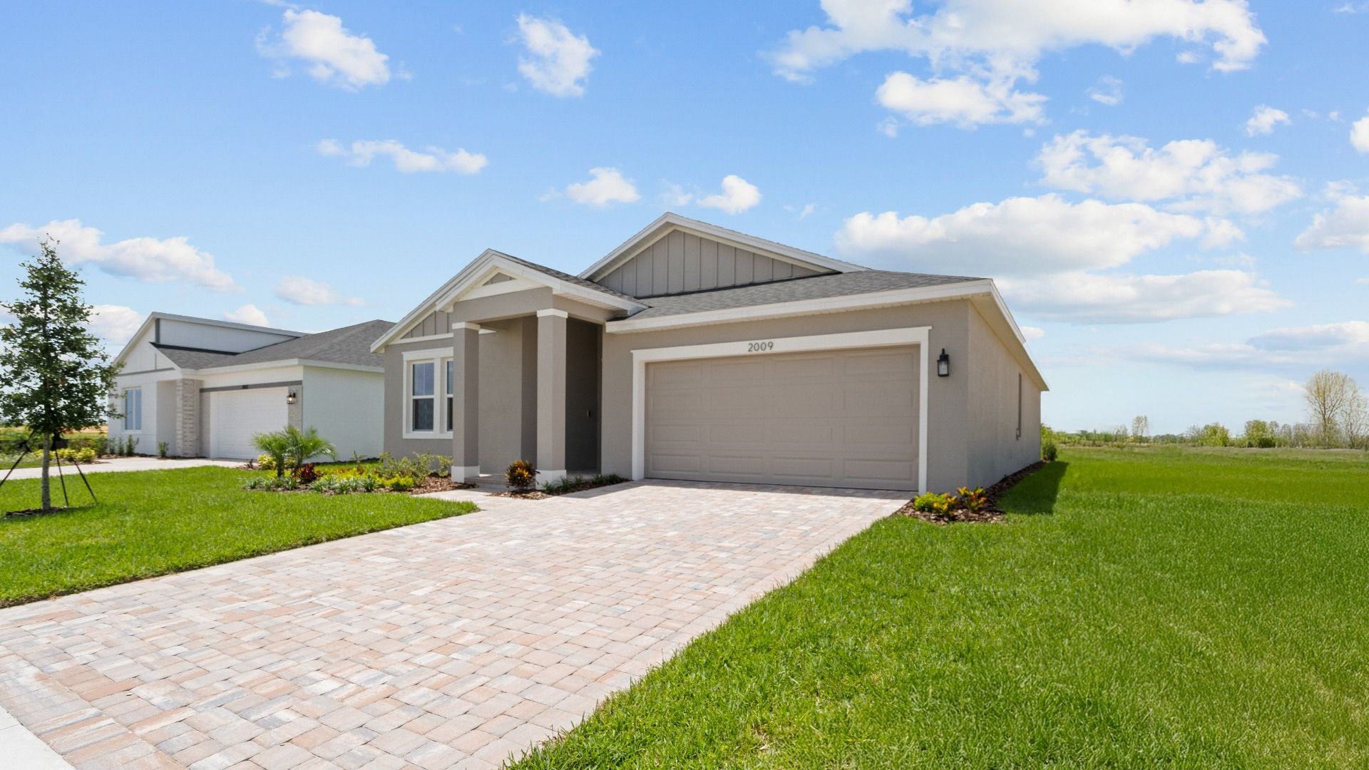 Buttonwood model coastal elevation featuring a tan exterior and spacious two-car garage