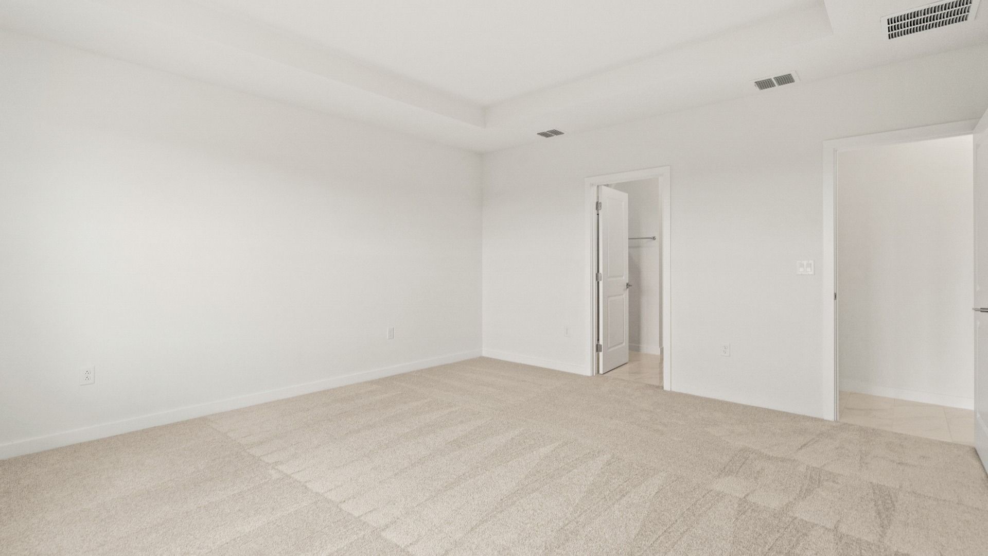 Primary bedroom with tray ceiling, plush carpet, and private access to the ensuite bath in the Castaway model by DRB Homes