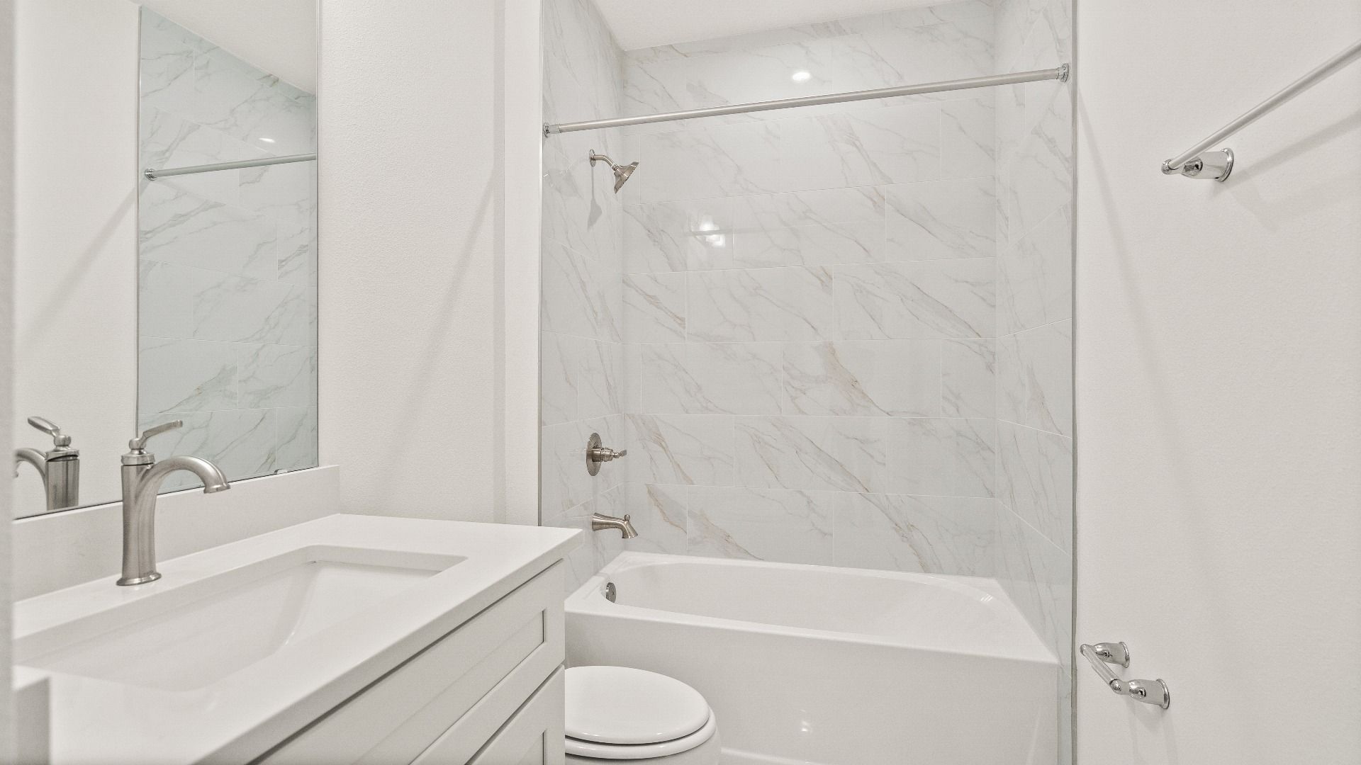 Modern secondary bathroom with white vanity and marble-style tile accents in the Castaway model