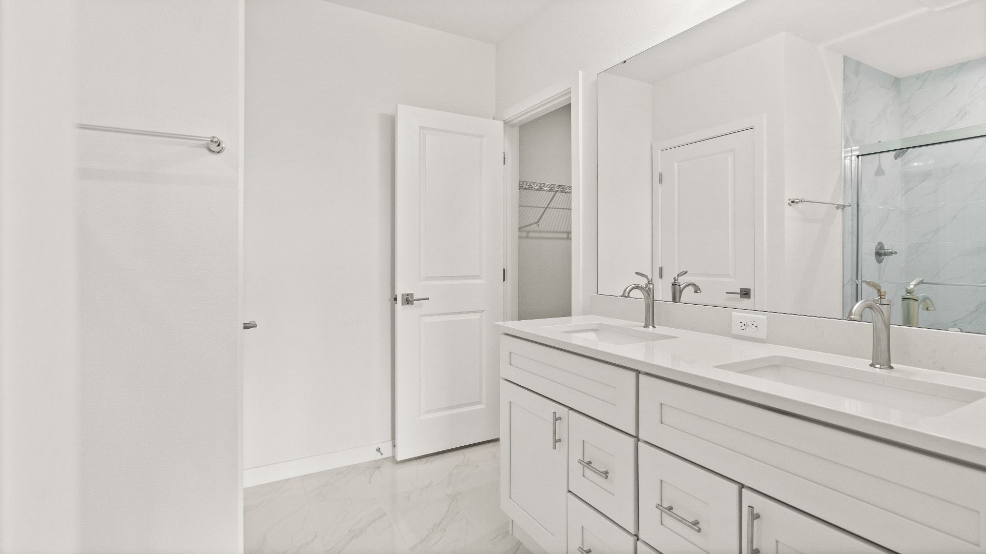 Spacious primary bathroom with double-sink vanity, chrome fixtures, and marble-style tile accents in the Castaway model