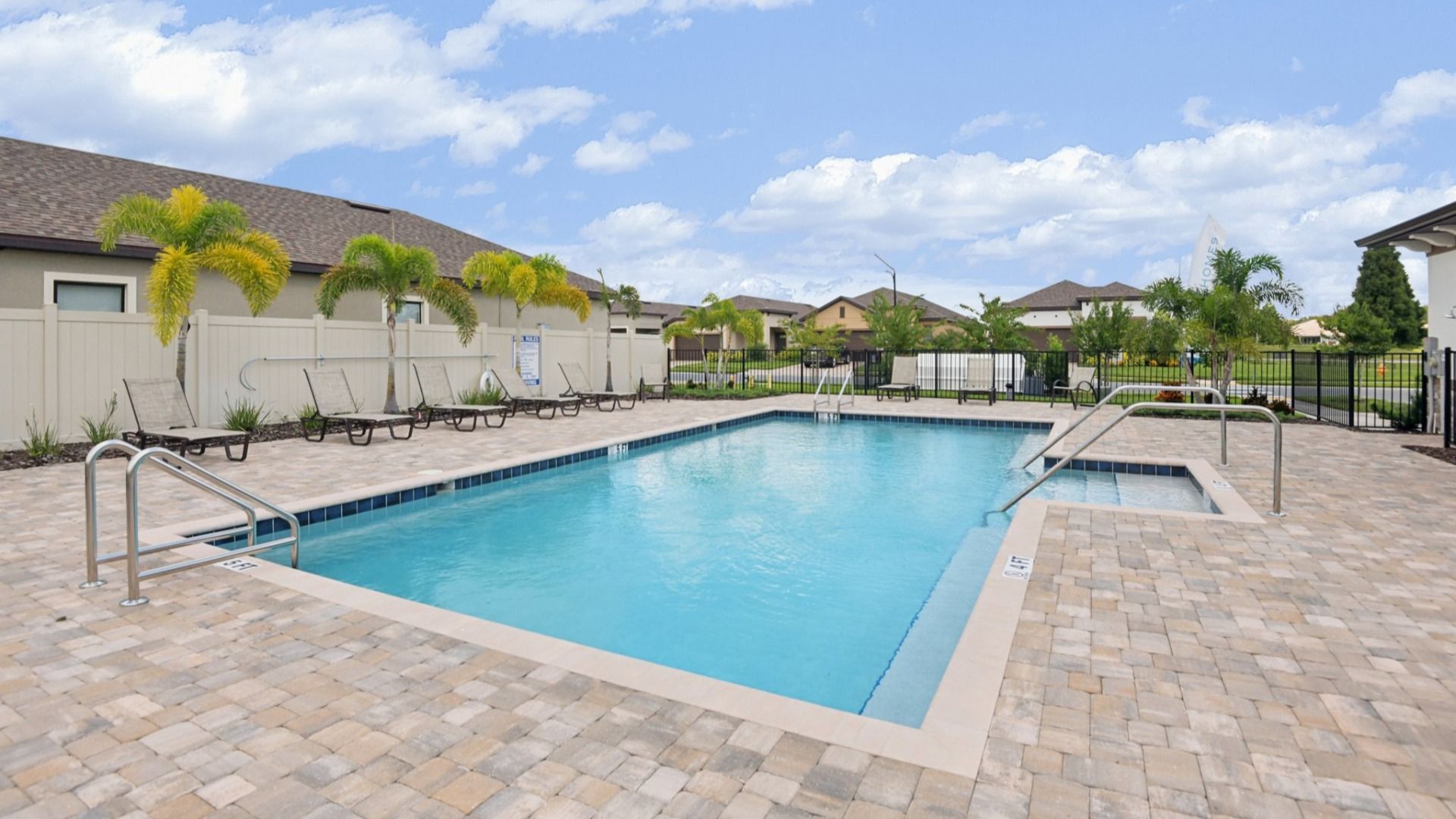 Resort-style swimming pool with sundeck, lounge chairs, and palm trees at Grasslands West in Lakeland, FL.