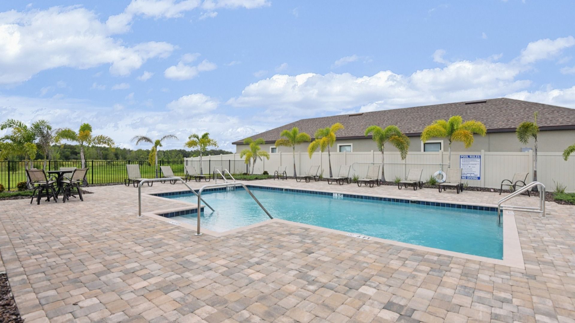 Relax and refresh at the resort-style pool at Grasslands West, complete with sundeck seating and palm-lined views.