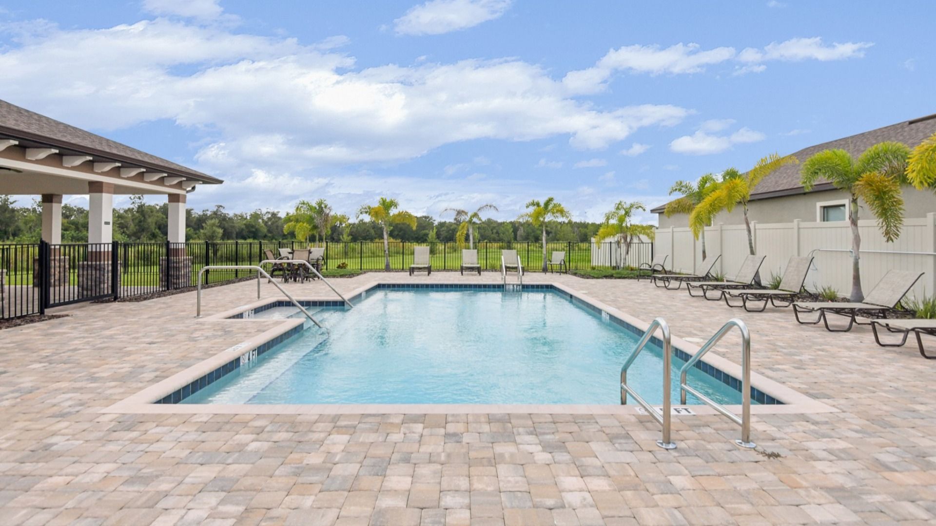 Take in the sunshine at the Grasslands West pool, featuring lounge chairs, palm trees, and pavilion views.