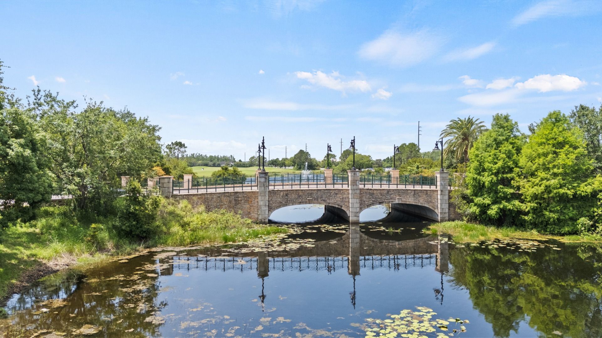 Lake Nona Bridge in Orlando, FL a stone-arch bridge surrounded by lush greenery and water near Cyrene at Harmony DRB Homes.