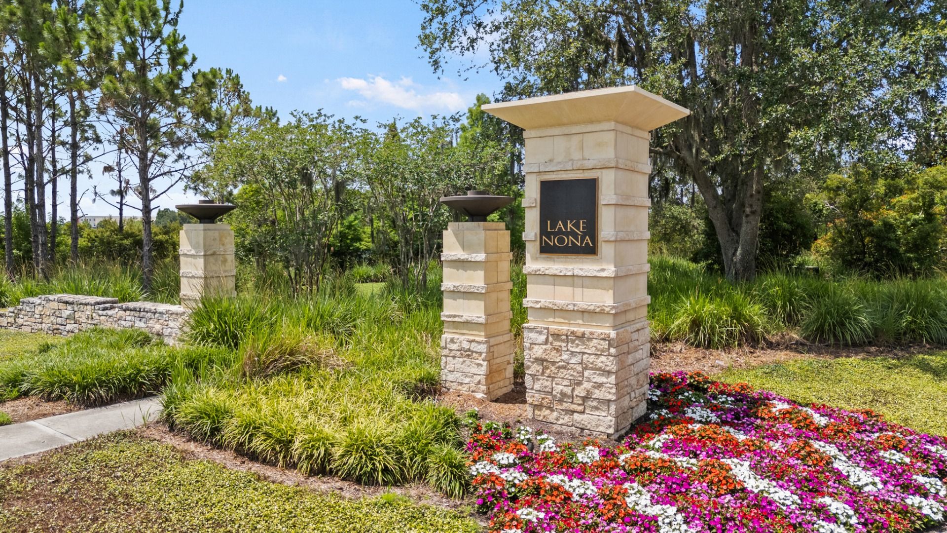 Lake Nona entrance sign in Orlando, FL, surrounded by colorful flowers and lush landscaping near DRB Homes Cyrene at Harmony