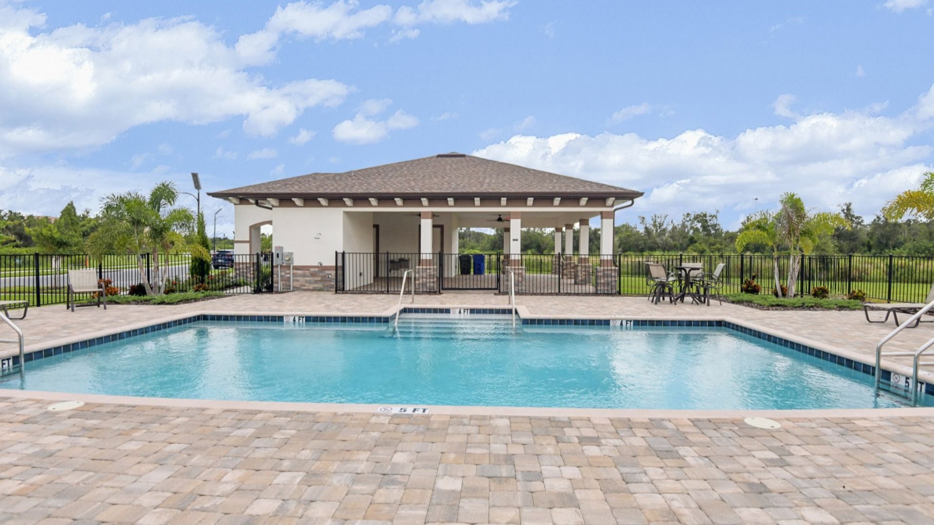 Resort-style swimming pool with sundeck, lounge chairs, and palm trees at Grasslands West in Lakeland, FL.