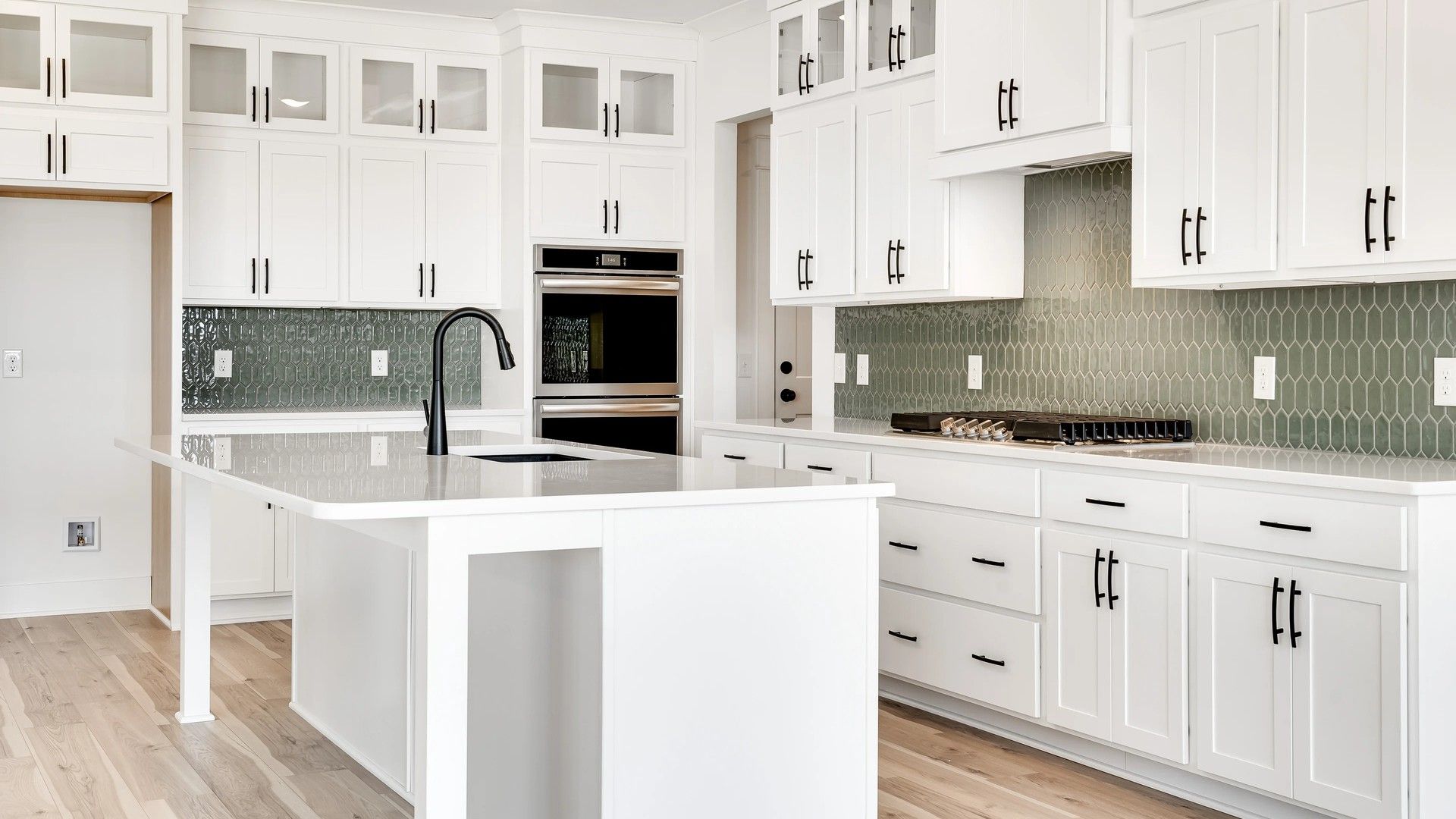 Exquisite white cabinetry and chic green backsplash define this Northridge Park kitchen's elegance and sophistication.