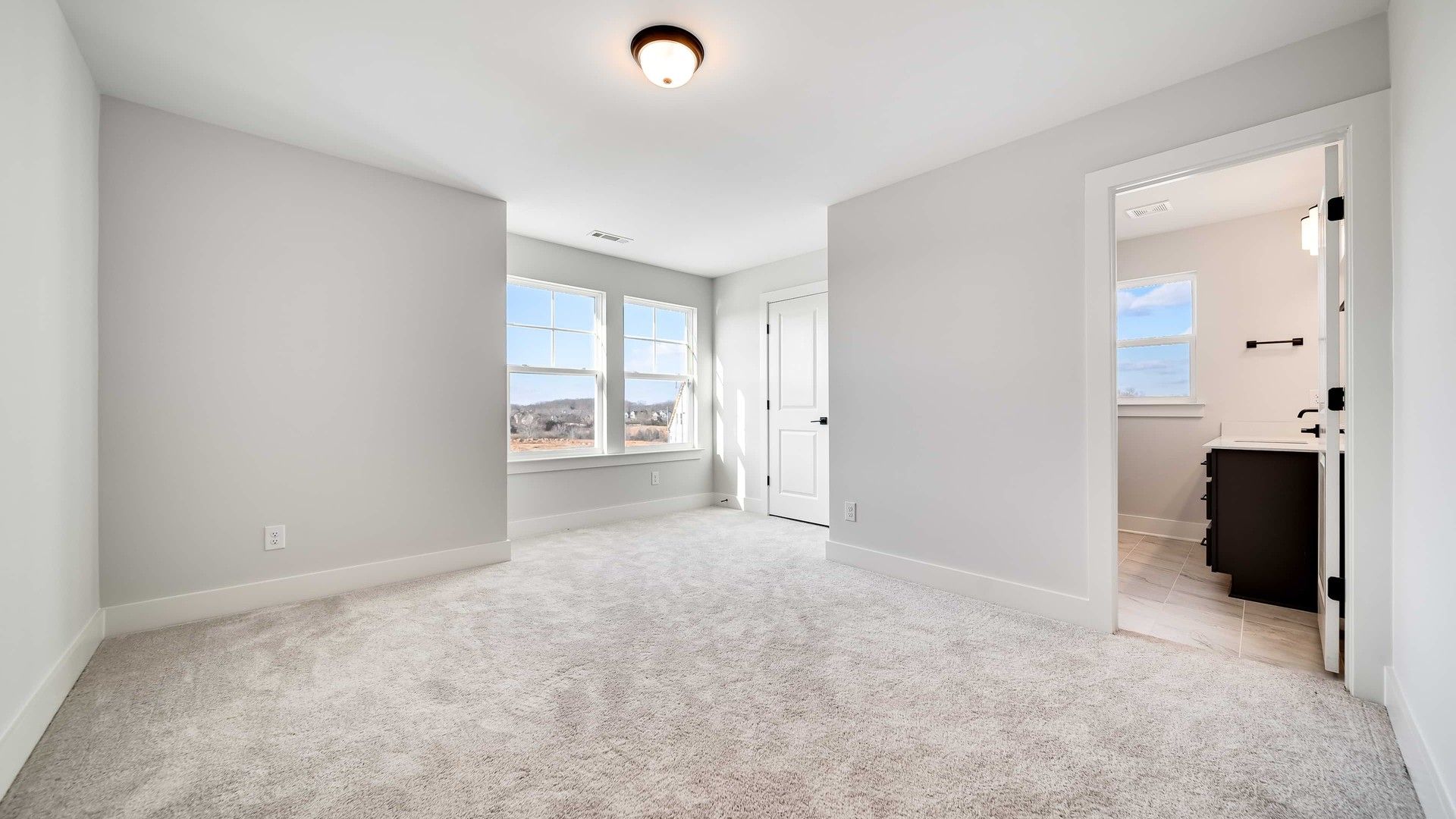 Luxurious bedroom with elegant plush carpet, large windows offering scenic views. Located in Richvale Estates.