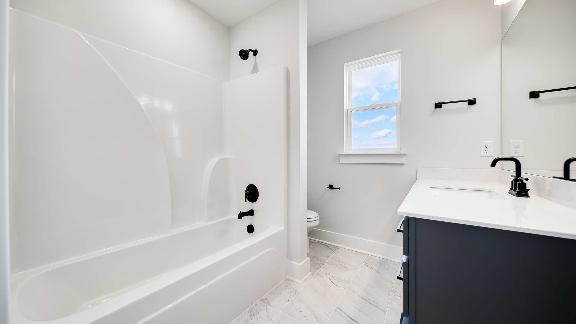 Luxurious bathroom featuring sleek black fixtures, elegant marble tile, and bright ambiance. Richvale Estates.