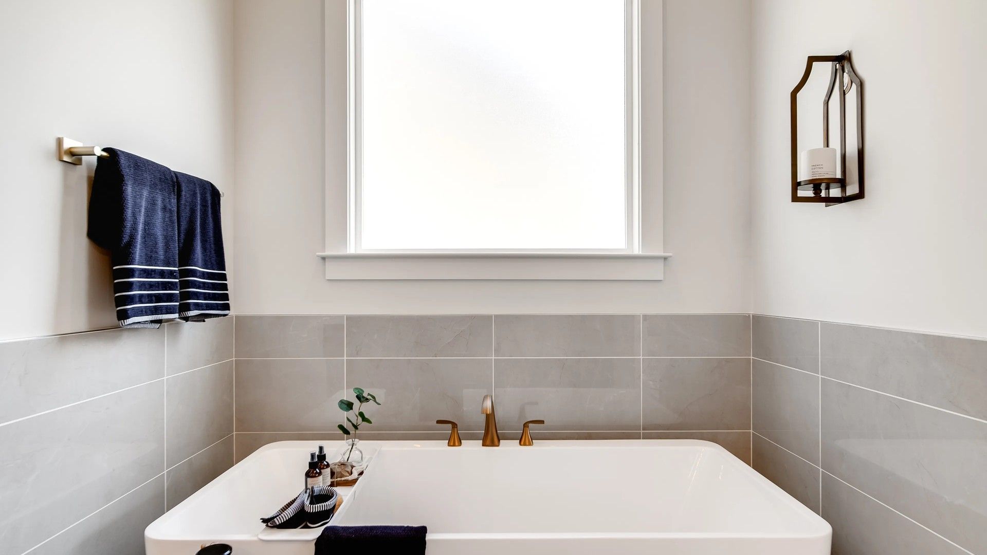 Indulge in the luxury of a freestanding tub with elegant brass fixtures and gray tiles in Shelton Square.