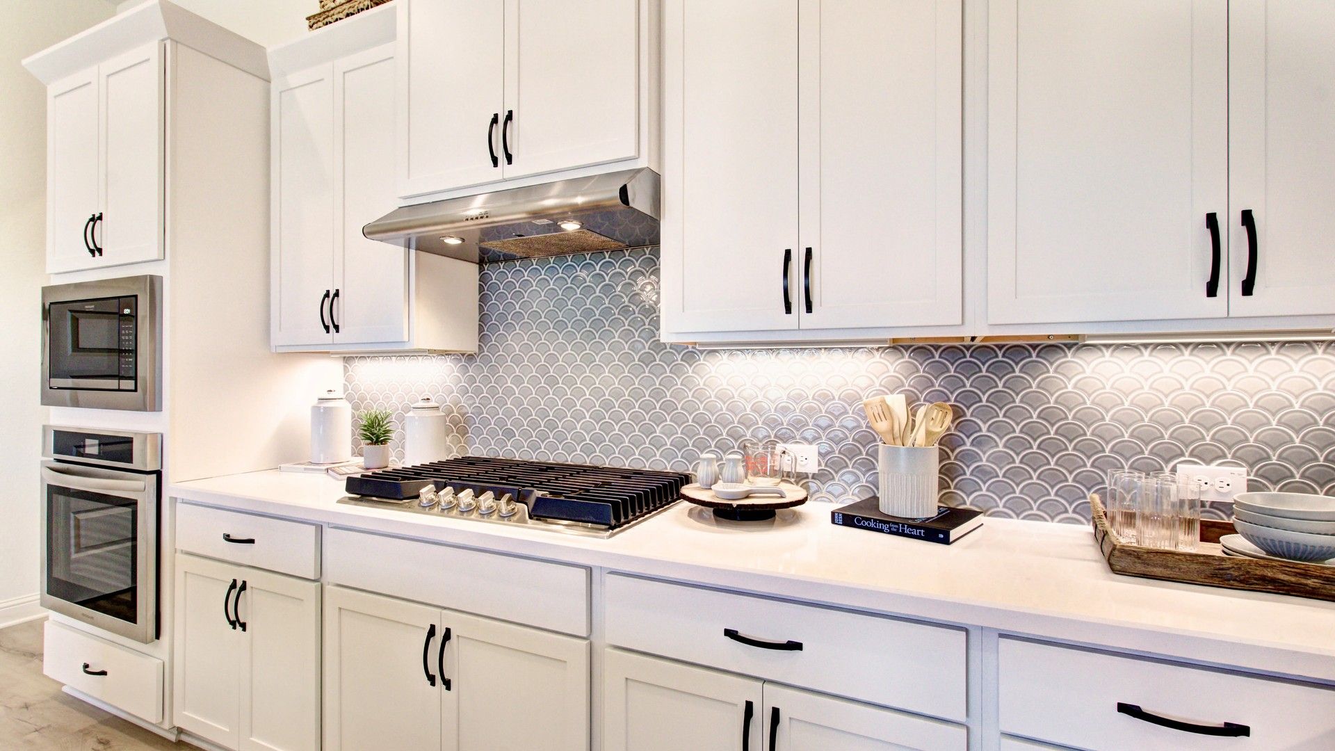Experience luxury with custom white cabinetry and fish scale tile in Veranda’s sophisticated kitchen.