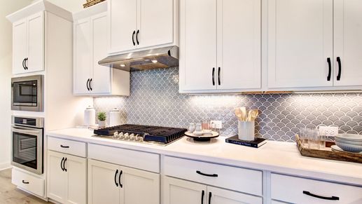 Experience luxury with custom white cabinetry and fish scale tile in Veranda’s sophisticated kitchen.