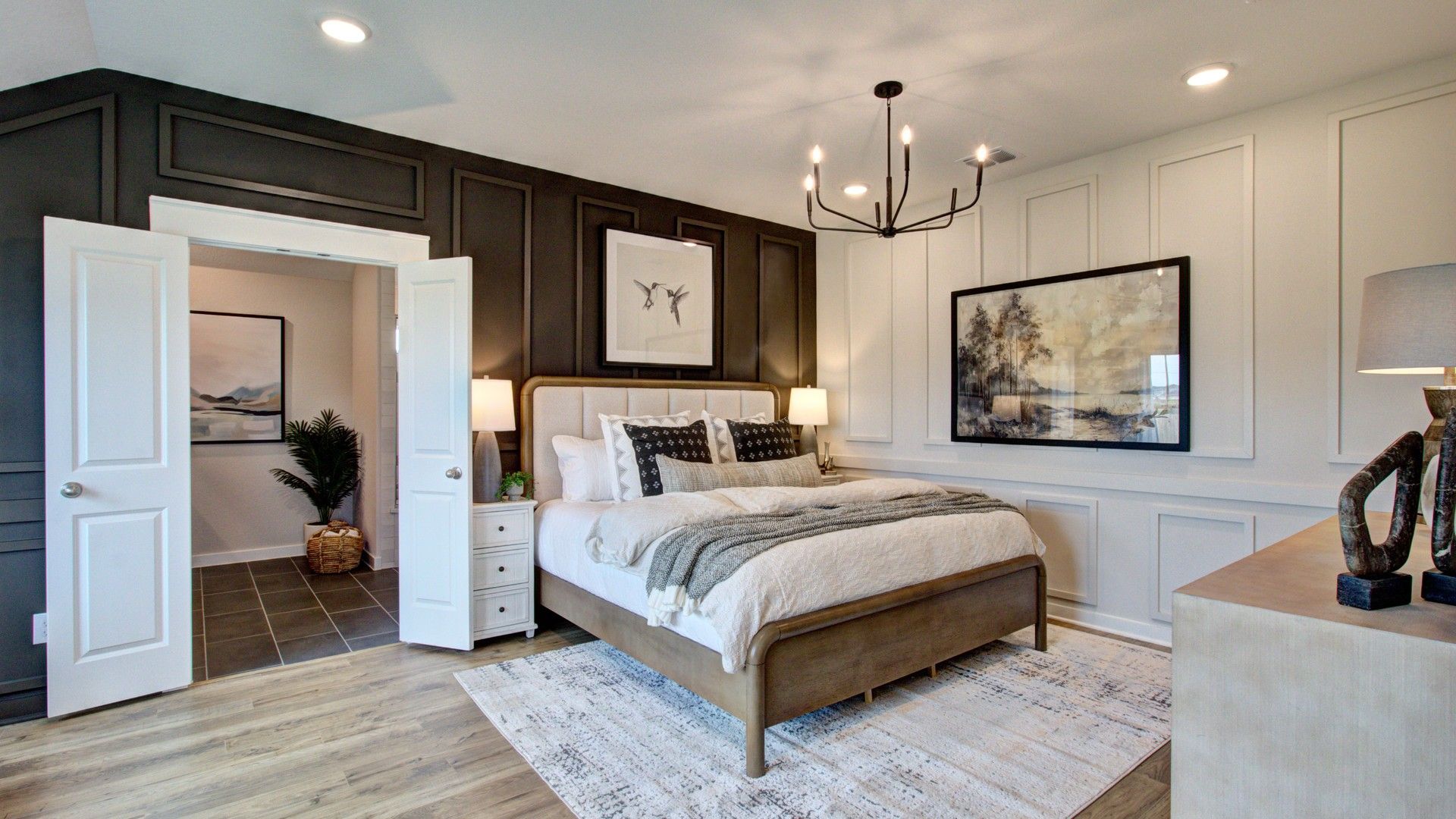 Prairie Green bedroom boasts chic black panel wall, modern chandelier, and rich wood flooring for a refined aesthetic.