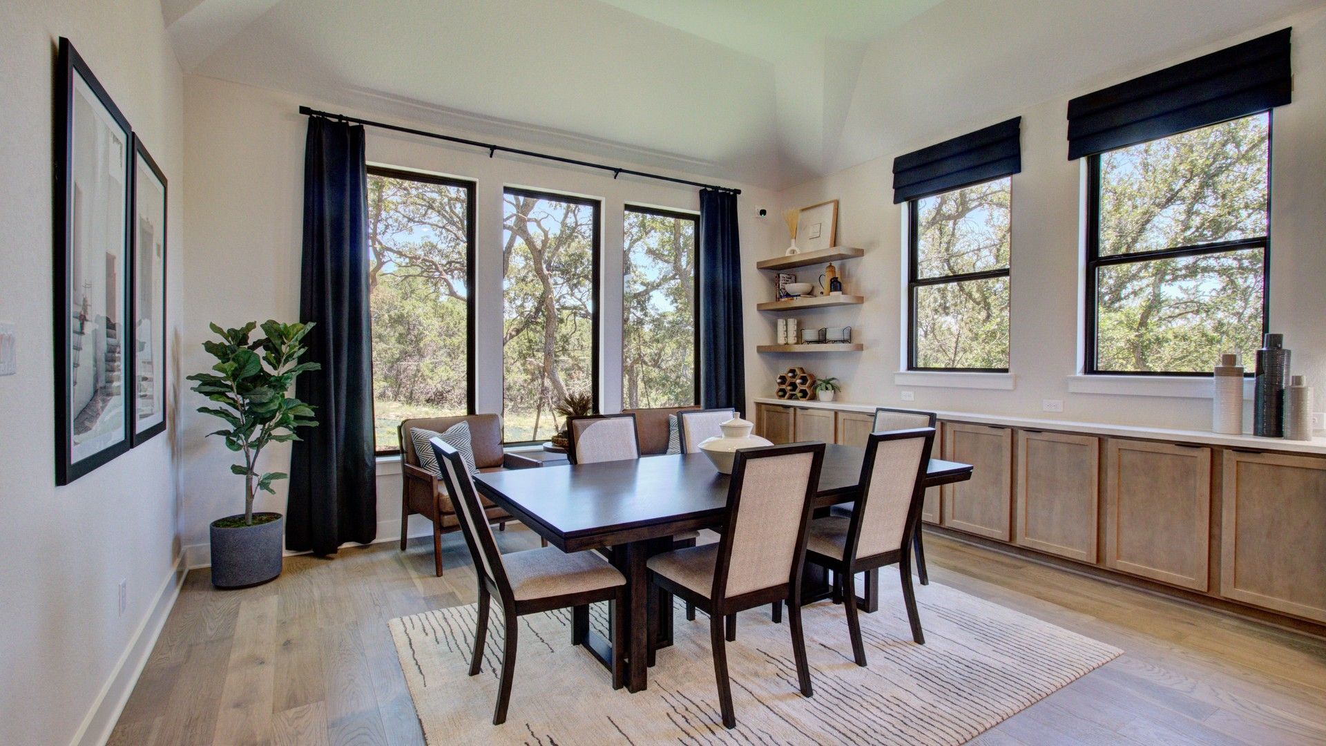 Sunlit dining room features expansive windows, chic shelving, and refined wood finishes. Verandas at the Rim, Texas.