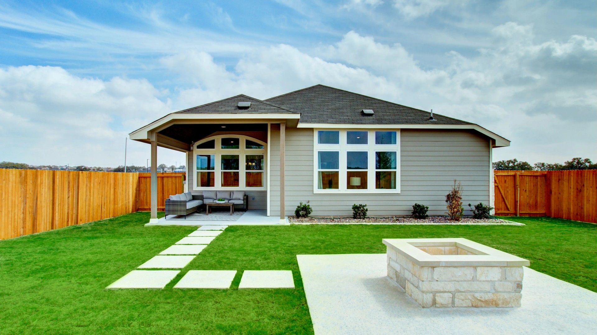 Elegant gray siding, expansive windows, and inviting fire pit in Veranda Community enhance luxury living.