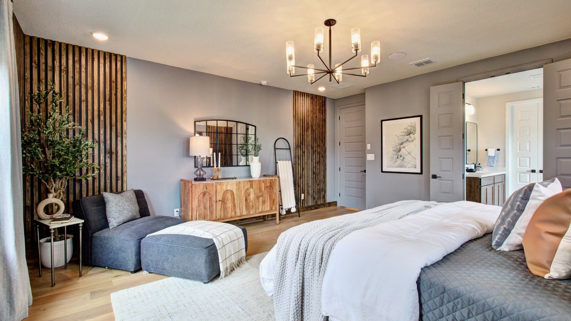 Elegantly crafted wood accents and a striking chandelier elevate this Sunflower Ridge master suite.