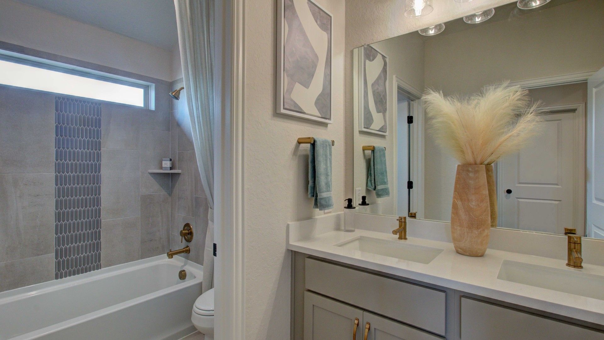 Elegant dual sinks, modern brass fixtures, and chic tile design elevate this Enclave at Meyer Ranch bathroom.