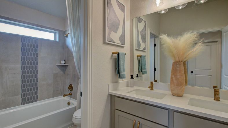 Elegant dual sinks, modern brass fixtures, and chic tile design elevate this Enclave at Meyer Ranch bathroom.
