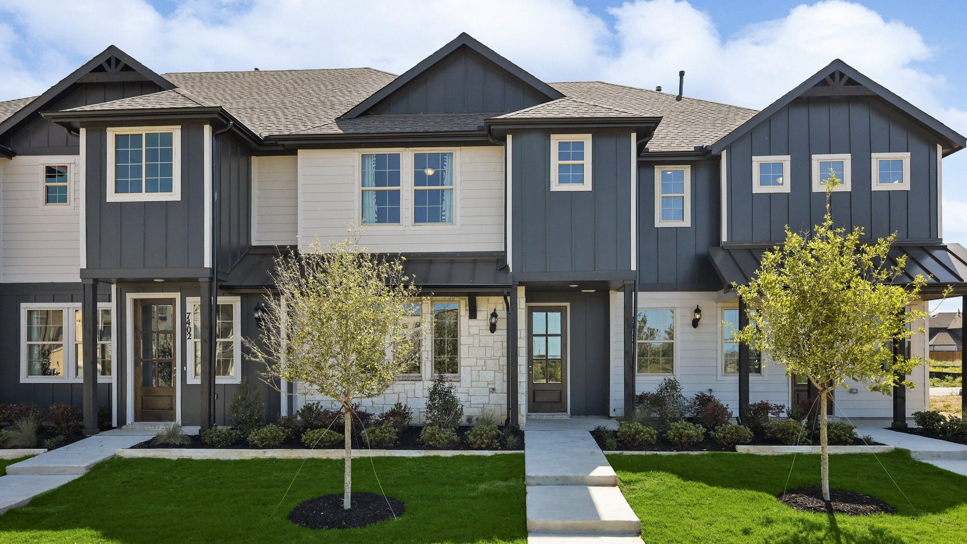 Luxurious townhouse in Hawkes Cove showcases sleek gray siding, elegant white trim, and expansive windows.