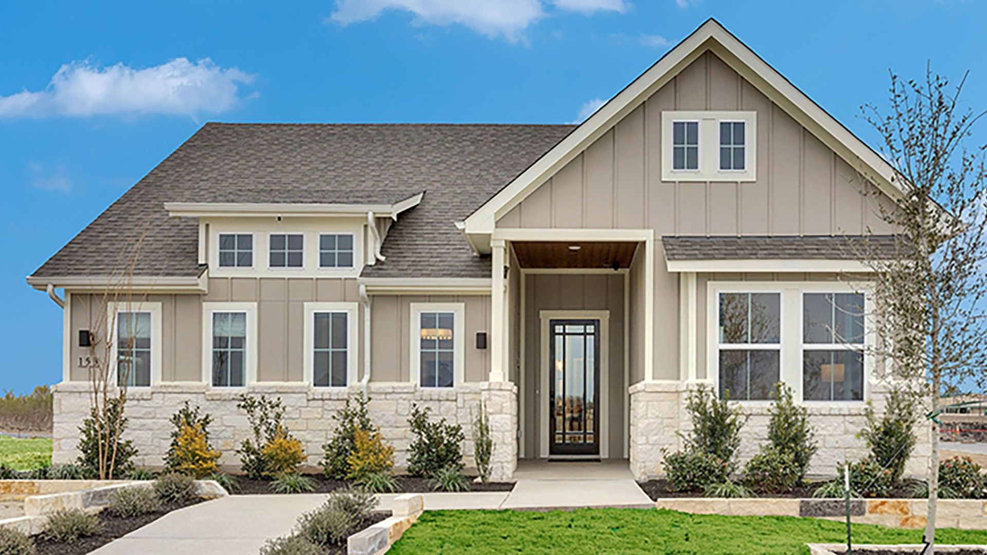 Elegant stone façade, lush landscaping, and gabled roof grace this Spring Creek residence.