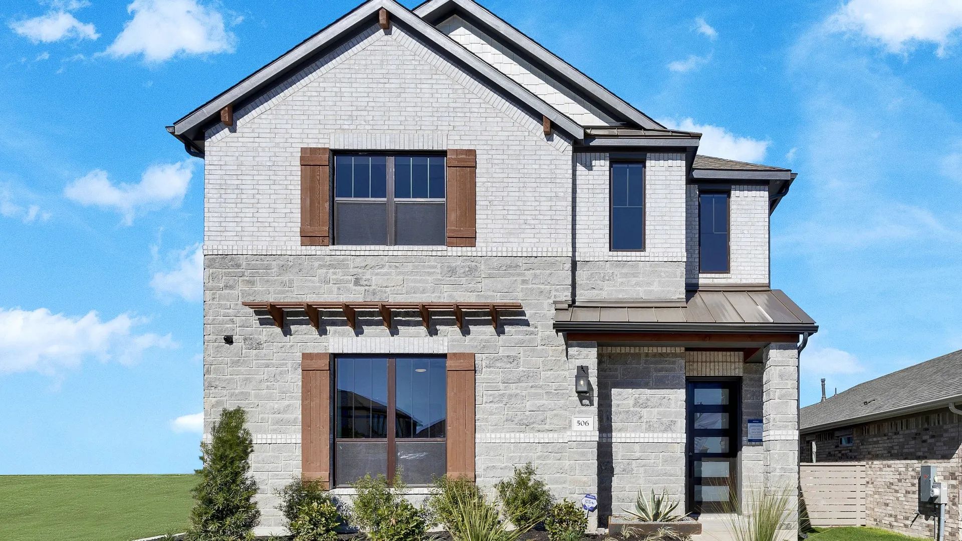 Elegant brick exterior with refined stonework and rich wooden accents in Flora community, exuding luxury.