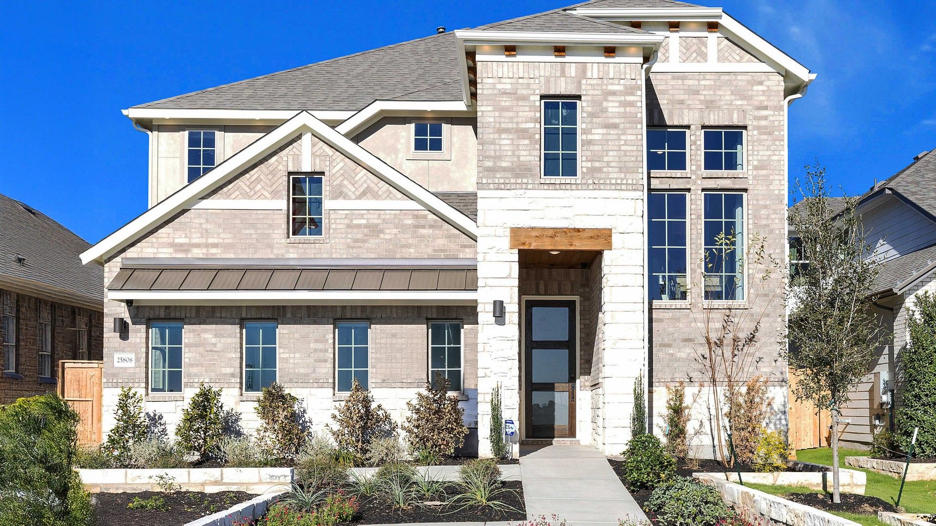 Elegant two-story home features exquisite brickwork, large windows, and refined stone facade in Briarwood community.