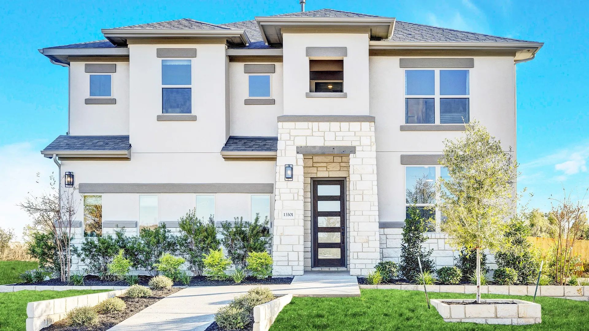 Elegant stone facade and expansive windows define this Creeks Crossing luxury home, showcasing modern architectural brilliance.