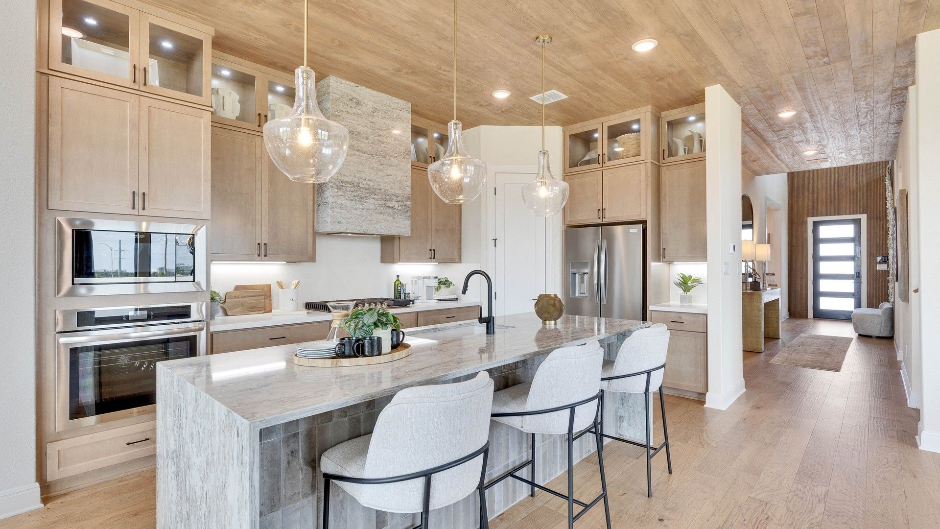 Luxurious kitchen featuring marble island, wood cabinetry, and chic pendant lighting in Lakeside Meadows.