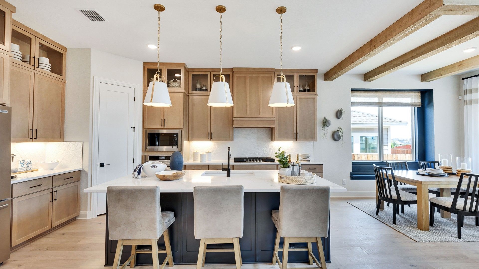 Exquisite Sunfield kitchen features elegant wood cabinetry, chic pendant lighting, and stylish exposed ceiling beams.