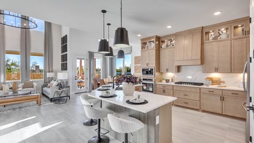 Sophisticated kitchen boasts sleek cabinetry, island seating, and expansive windows in Creeks Crossing location.