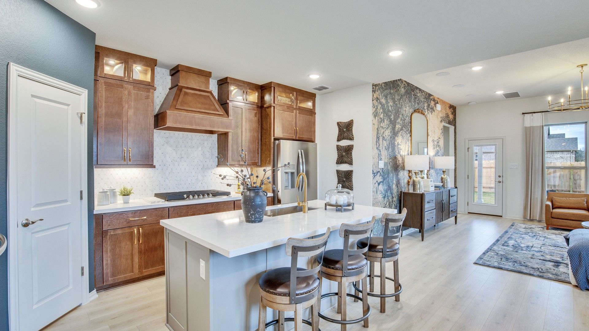 Luxurious marble backsplash and rich wood cabinetry enhance this Opal Ranch open-concept kitchen.