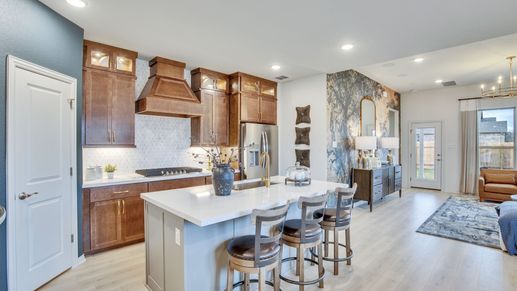 Luxurious marble backsplash and rich wood cabinetry enhance this Opal Ranch open-concept kitchen.