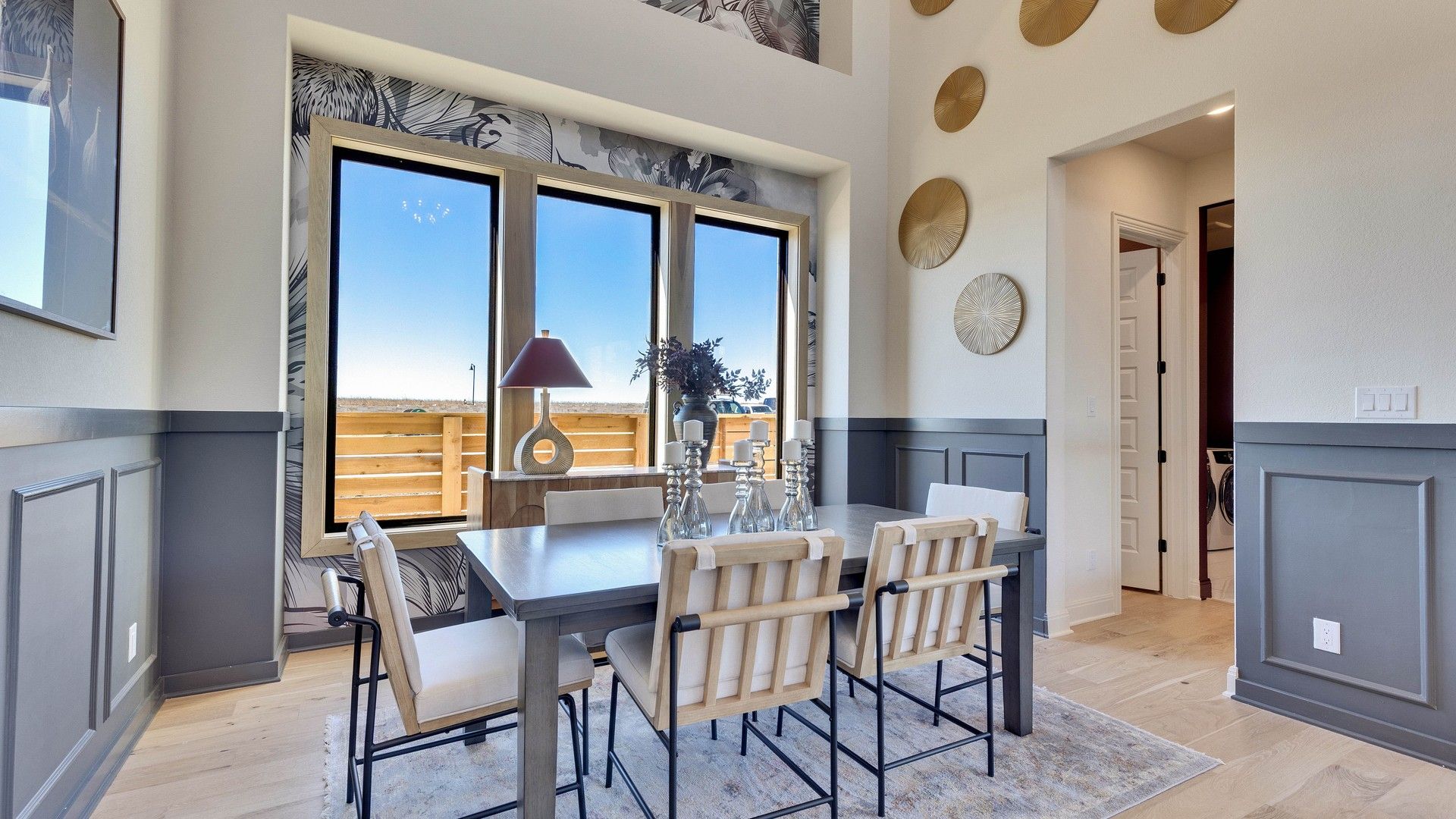 Elegant dining room with expansive windows and chic wainscoting, offering panoramic views in Flora community.