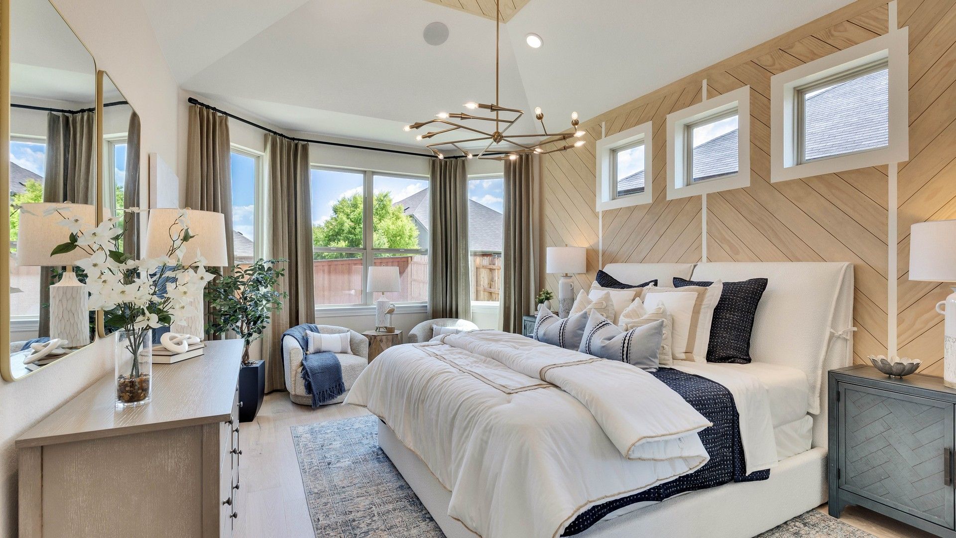 Experience elegance in Sunfield with this bedroom's chevron wood accent wall and plush details.