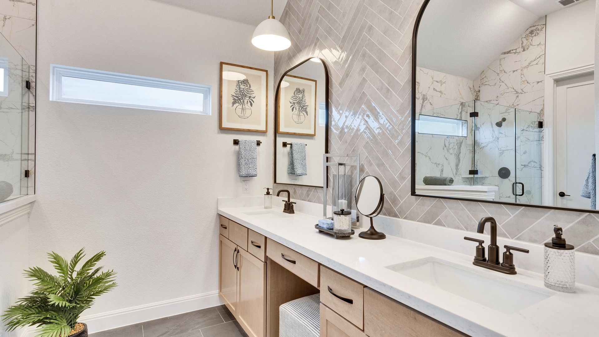 Luxurious bathroom features herringbone tile wall, marble shower, and custom cabinetry in Spring Creek.