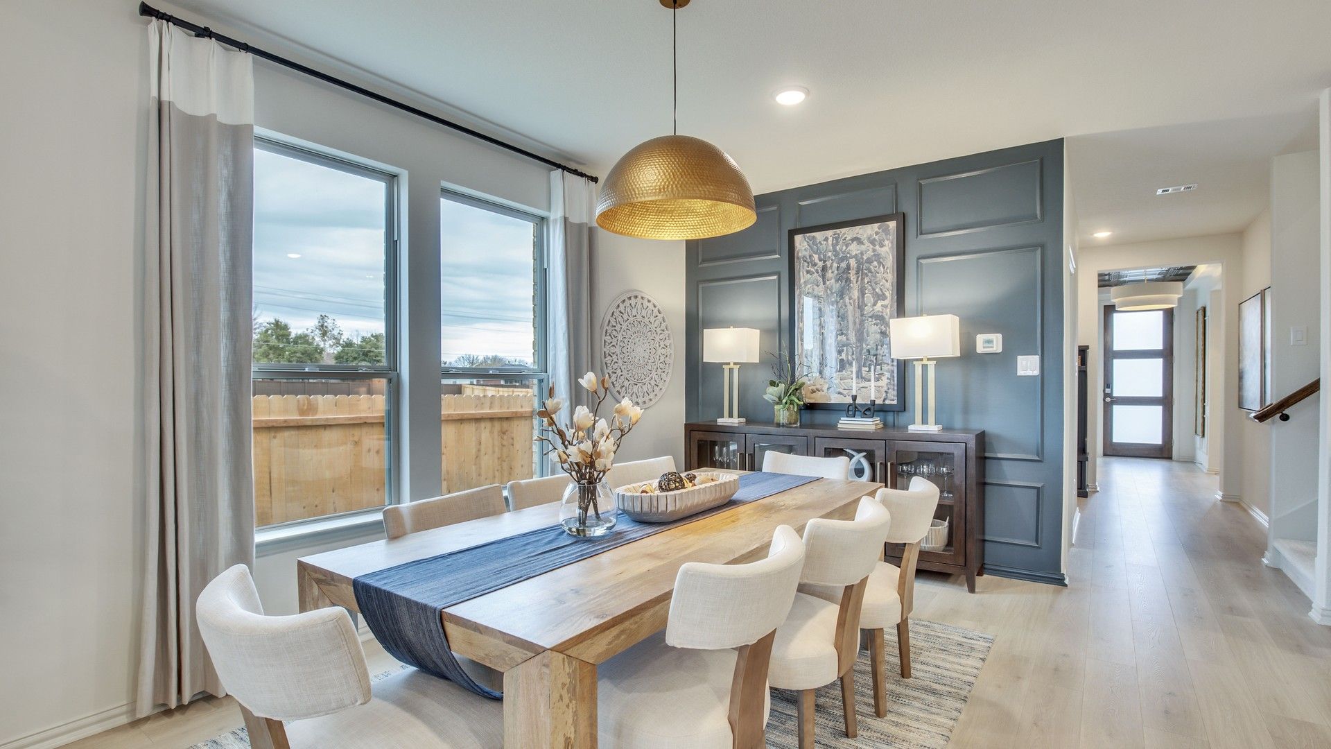Elegant wooden dining table, luxe blue accent wall, and chic lighting in Opal Ranch, TX.
