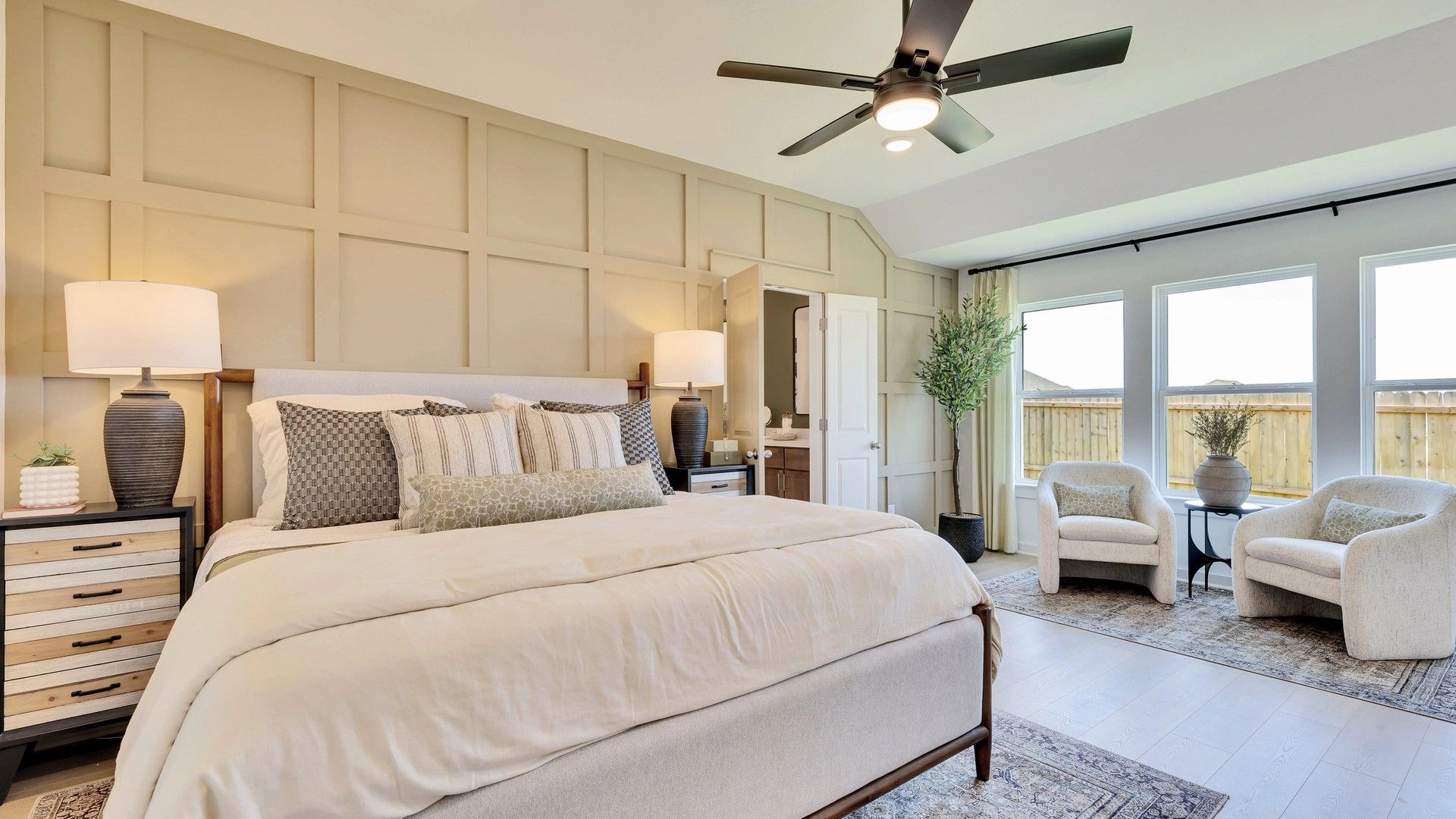 Luxurious bedroom in Hunters Glen, featuring elegant beige paneled walls and expansive windows for natural lighting.
