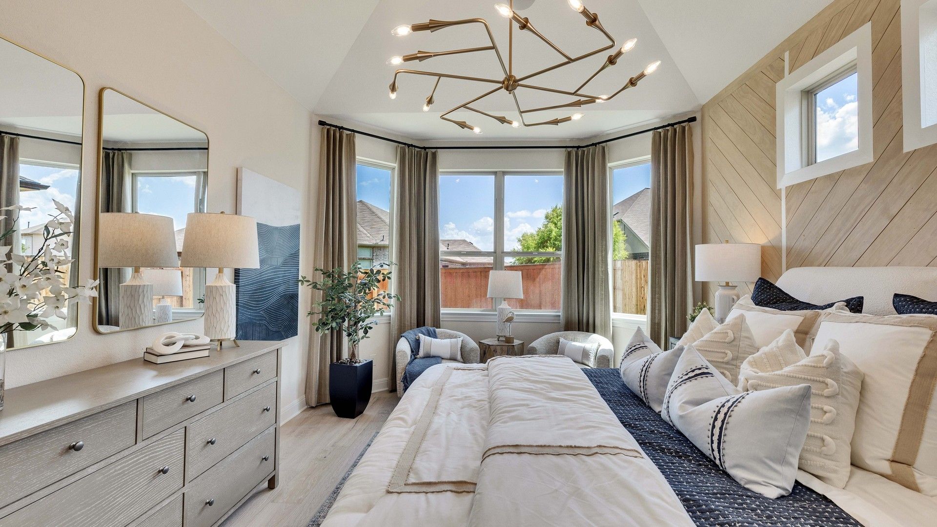 Sunfield bedroom boasts vaulted ceilings, chic lighting, and lavish decor. A serene, luxurious oasis awaits you.