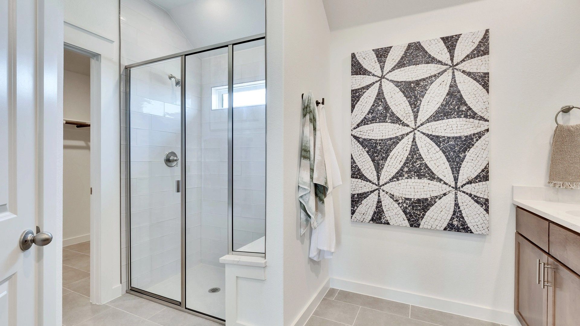 Luxurious bathroom features elegant glass shower, sleek mosaic design, and rich wood cabinetry in Hunters Glen.