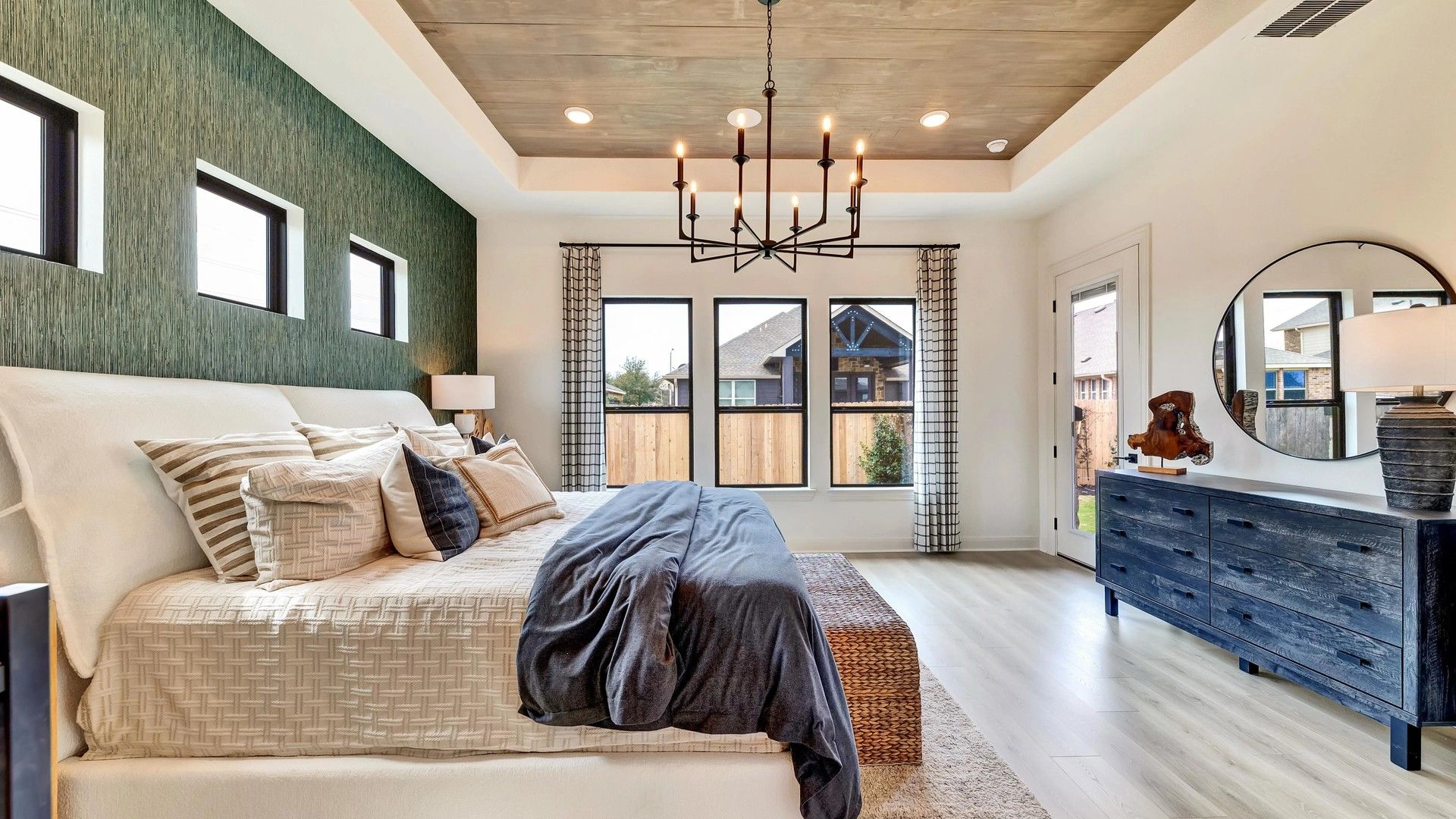 Sophisticated bedroom features textured accent wall, chic chandelier, and premium wood flooring. Hawkes Landing locale.