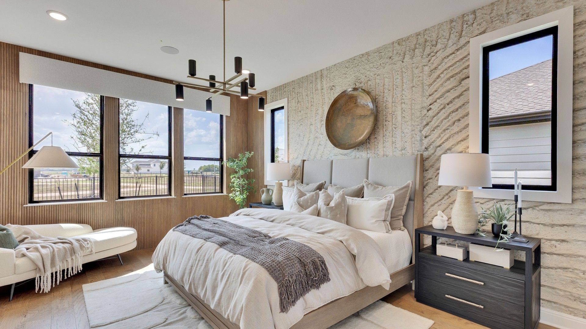 Elegant bedroom with textured accent wall and sleek chandelier, designed for luxury at Lakeside Meadows.