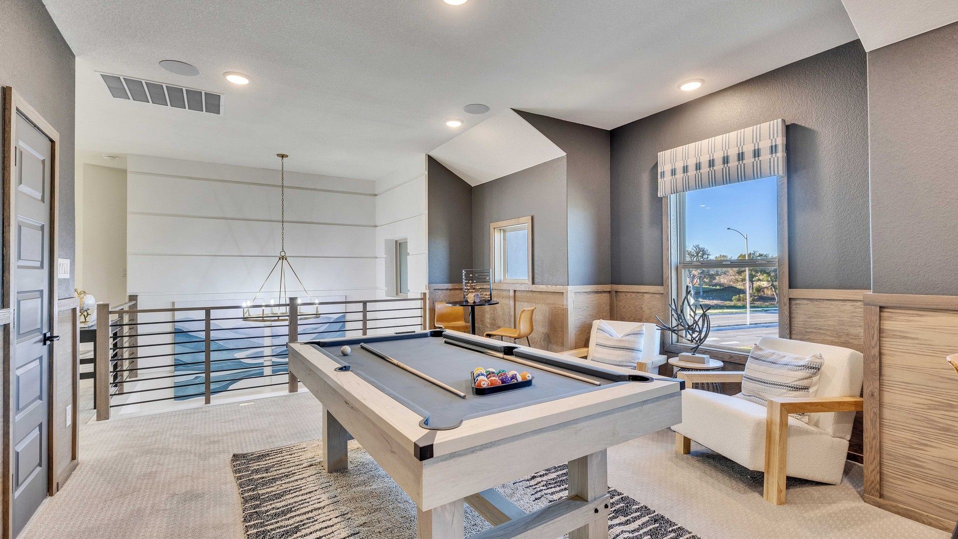 Enjoy elegant high-ceiling design with plush seating and a sleek pool table in Creeks Crossing's refined setting.