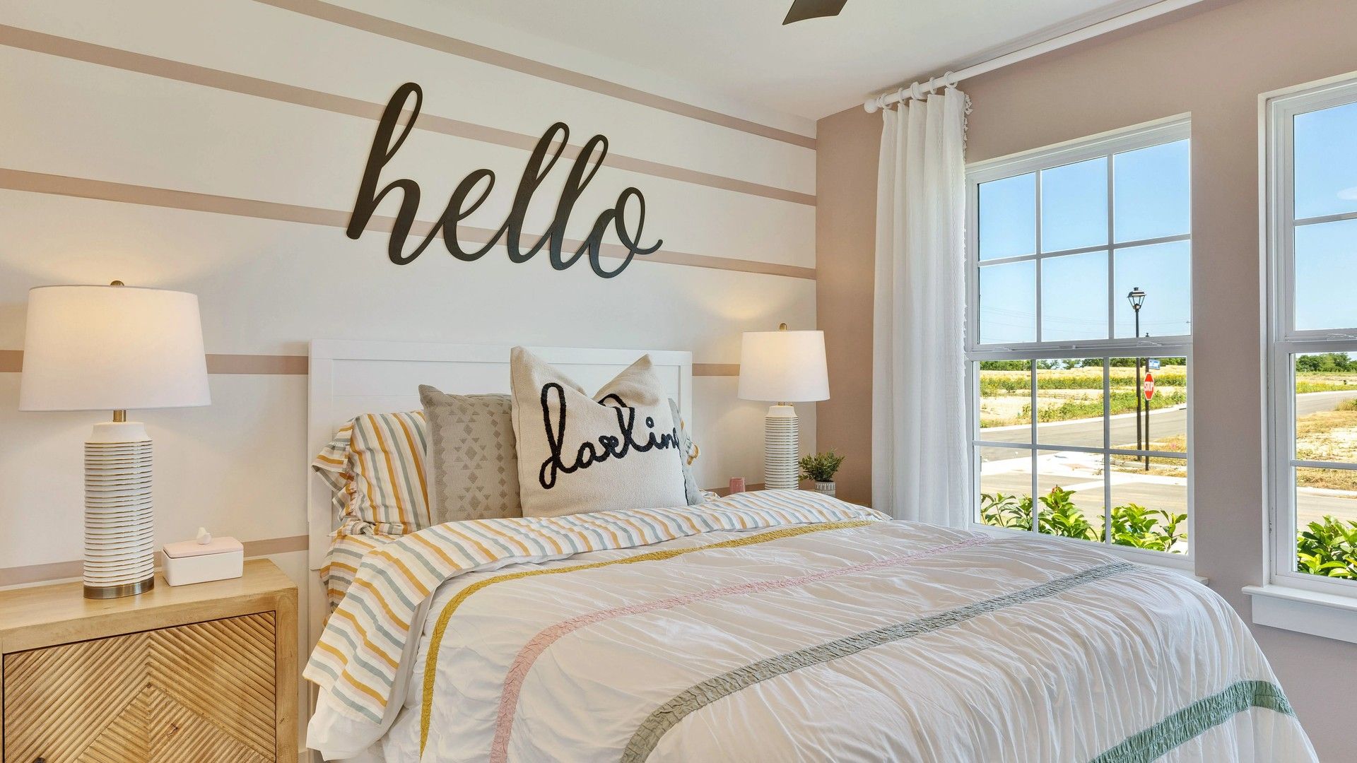 Luxurious bedroom features chic striped walls, high-end lighting, and vibrant bedding in Hunters Glen.