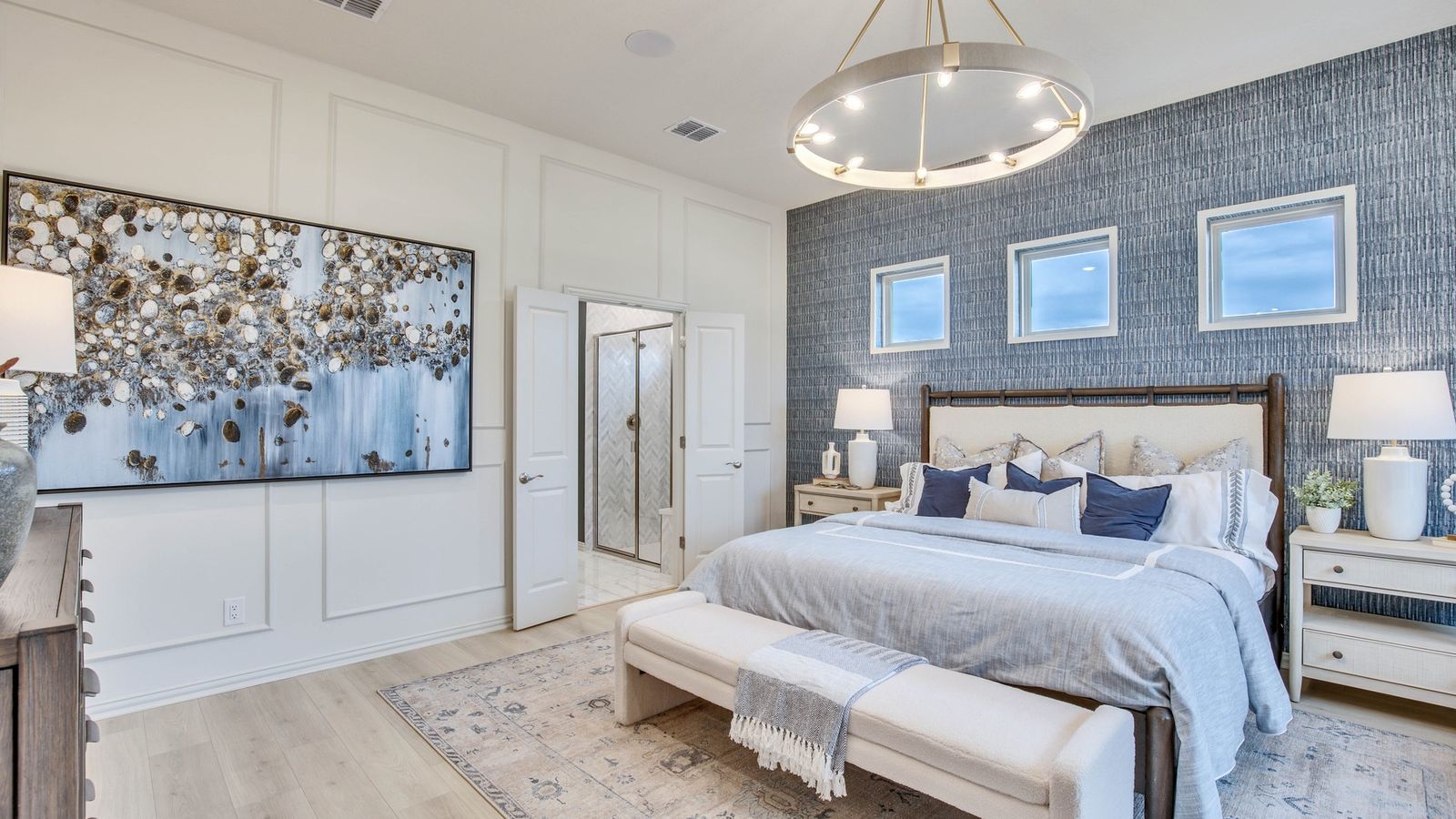 Sophisticated bedroom in Opal Ranch, featuring a striking chandelier and a textured blue accent wall for refined allure.